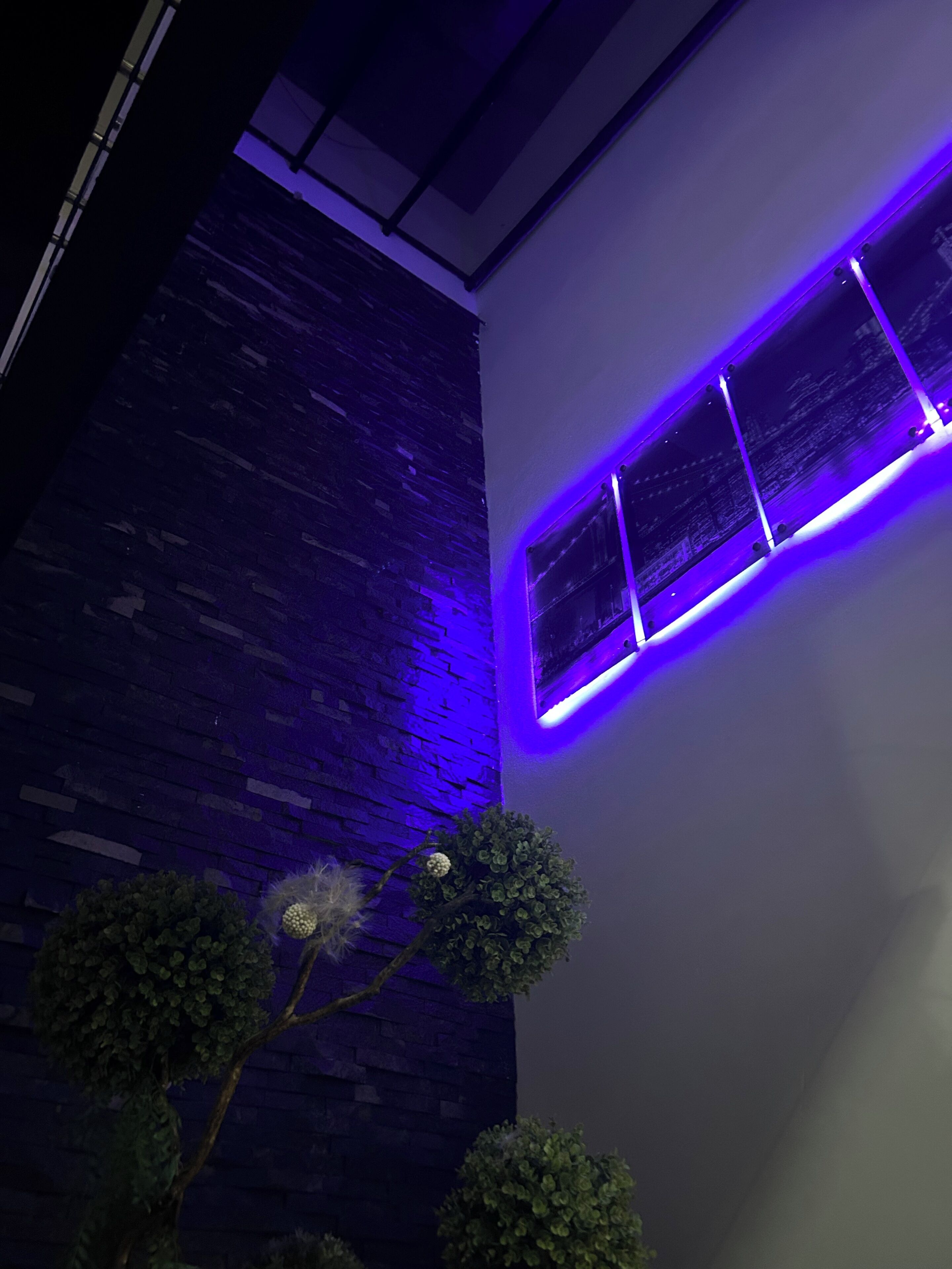 A modern interior with a brick wall and a purple-lit window.