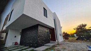 A modern two-story house with a stone facade and a flat roof. - Residence near the beach (Mezcales)