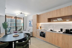 A modern kitchen with wooden cabinets, a built-in oven, and a countertop with a coffee maker. - Downtown Brickell - Desirable Location - We Host (Miami)