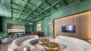 A modern lobby with curved sofas, a dining area, and a TV on the wall. - Downtown Brickell - Desirable Location - We Host (Miami)