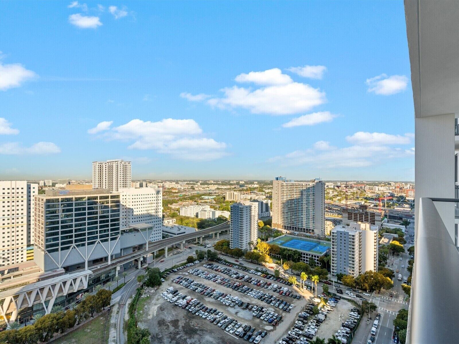 A high-rise building with a parking lot in the foreground and a cityscape in the background.