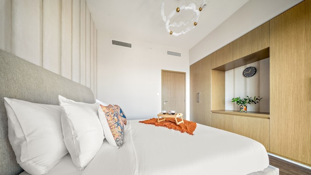 Une chambre à coucher moderne avec un grand lit, une table de chevet avec une horloge et une armoire en bois.