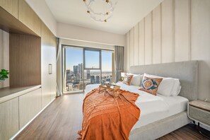 Een moderne hotelkamer met een groot bed, stadszicht en een houten kast.