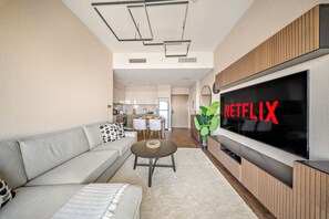 Ein modernes Wohnzimmer mit grauem Sofa, einem Couchtisch und einem an der Wand befestigten Flachbildfernseher.