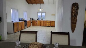 A spacious kitchen with wooden cabinets, a dining table with chairs, and a view of the outdoors through a window. - Spacious house located in Vieux Fort, few minutes from Hewanorra Airport (Vieux Fort)