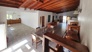 Un vaste espace de vie doté d’un haut plafond en bois, d’une table à manger et d’une cuisine située au fond de la pièce.