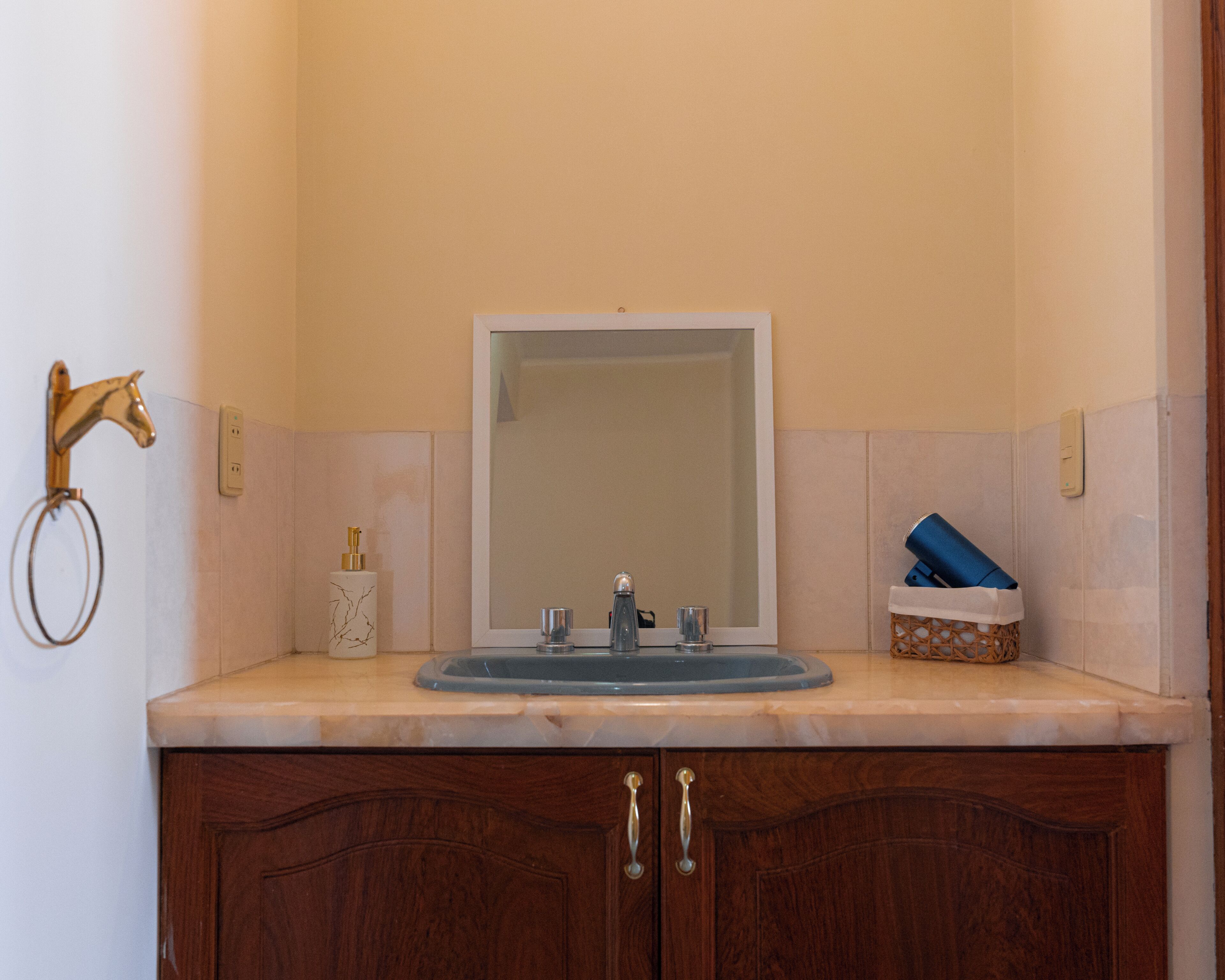 Un baño con lavamanos, espejo y armarios de madera.