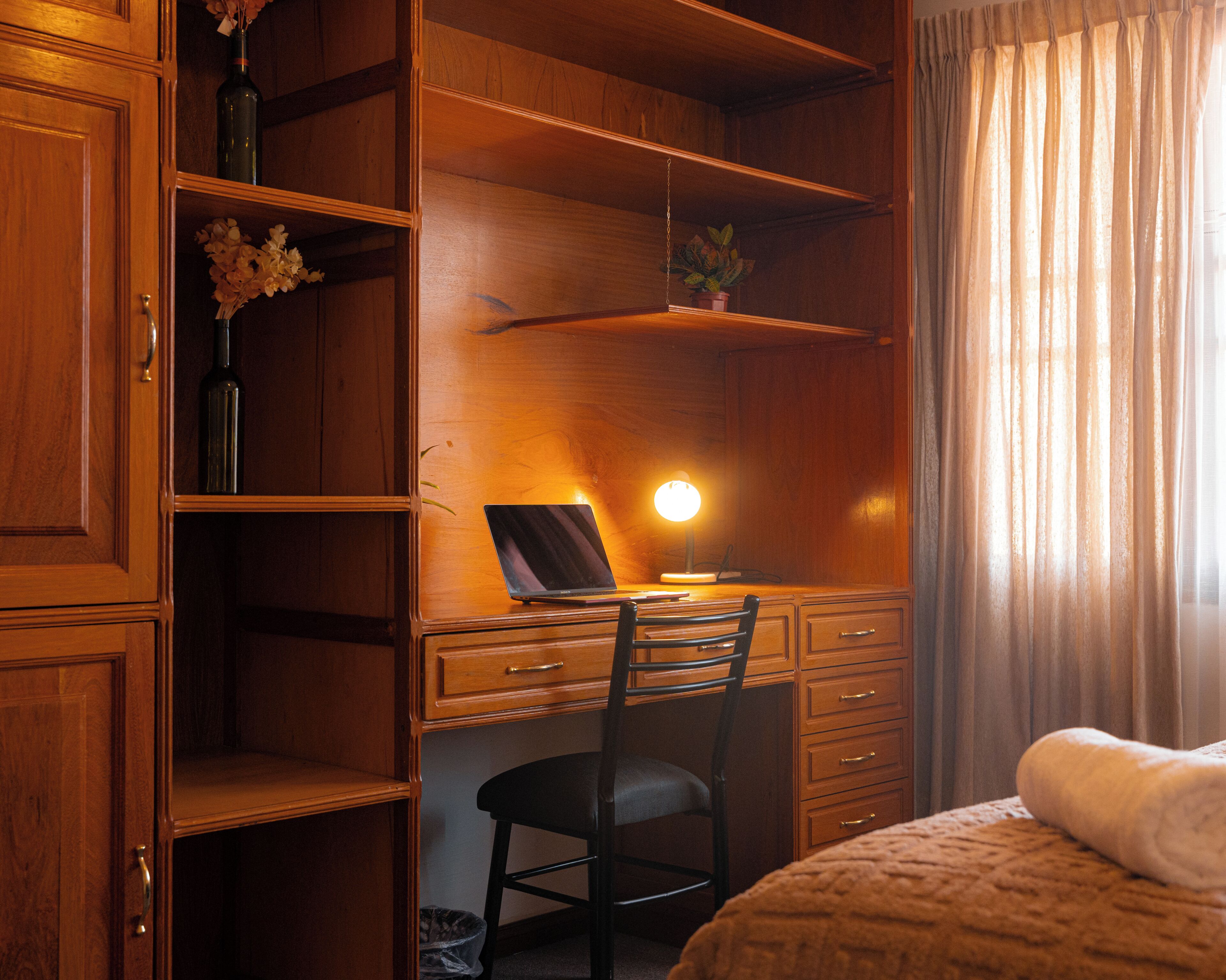 A wooden room with a desk, chair, and a bed.