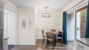 Een keuken met een eettafel, stoelen, een kroonluchter en uitzicht door een schuifdeur.