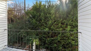 Een balkon met een metalen hekwerk met uitzicht op een dicht naaldbos.