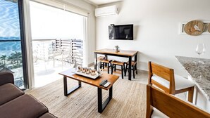 Un soggiorno moderno con balcone, un'area pranzo e una TV a parete.