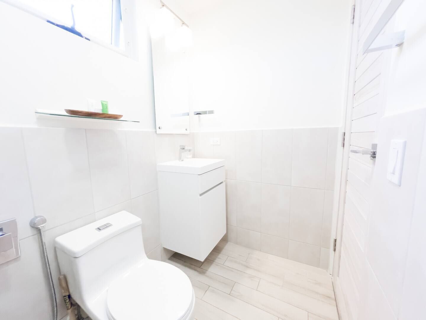 Un baño pequeño y blanco con inodoro, lavamanos y espejo.