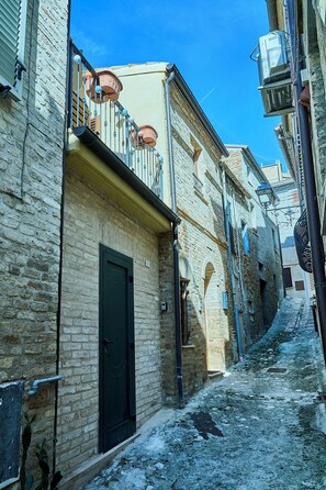 A narrow cobblestone street flanked by historic buildings with exposed brickwork and traditional balconies. - Casa Vicolo TerminIO / historic center / 15 minutes to the beach Adriatic Sea (Fermo)