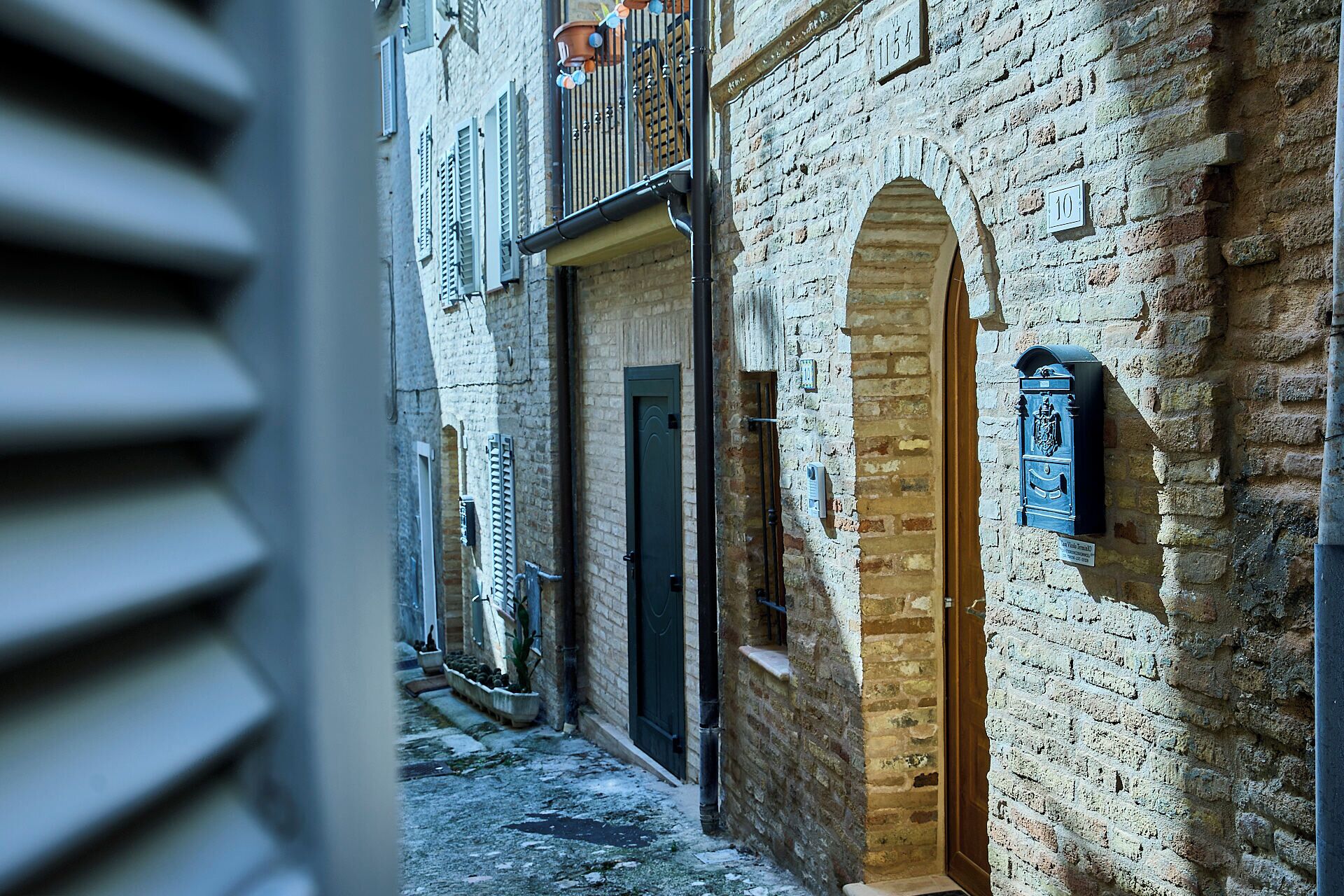 Una calle estrecha con edificios de ladrillo tradicional, un buzón y una puerta con un pequeño ventanal.