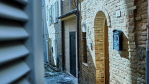 En smal gata med traditionella byggnader i tegel, en brevlåda och en dörr med ett litet fönster.