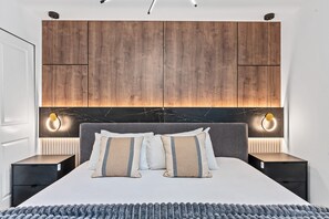 Ein Schlafzimmer mit einem hölzernen Kopfteil, zwei Nachttischen, einem Bett mit Kissen und Wandleuchten.