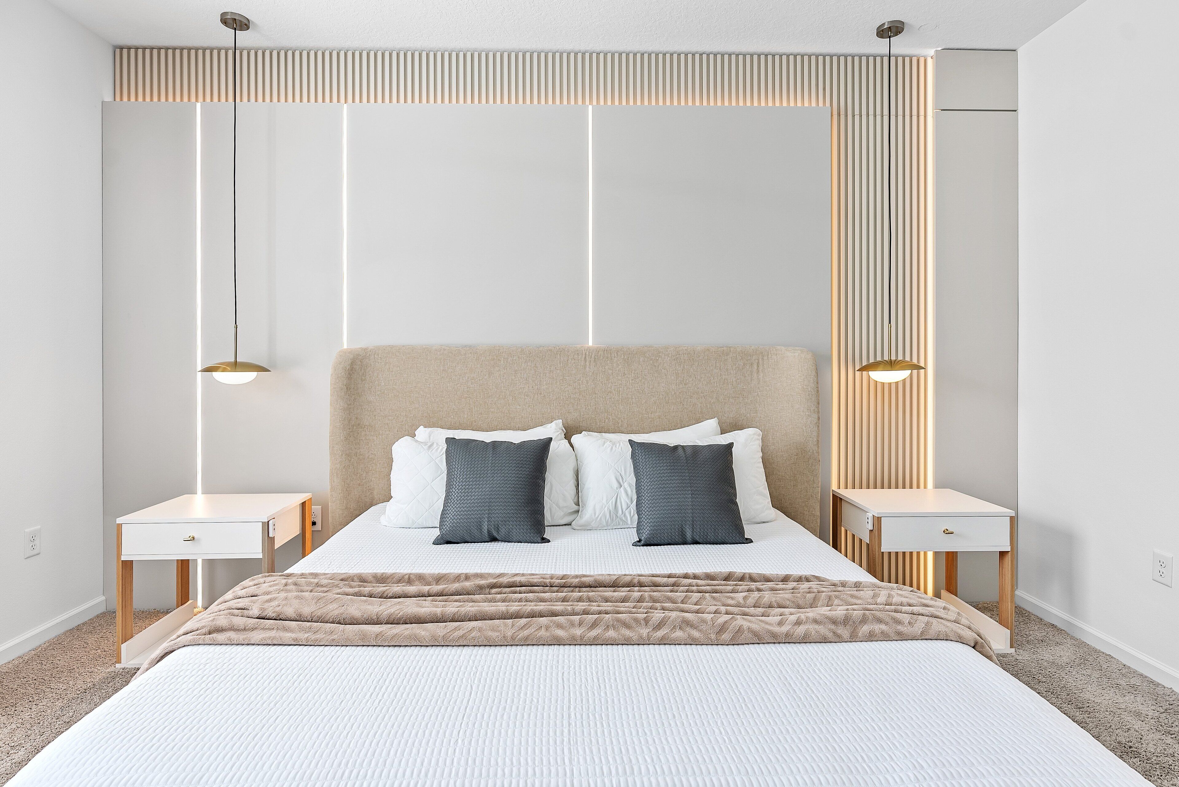 A modern bedroom with a large bed, two bedside tables, and a headboard with vertical lines.
