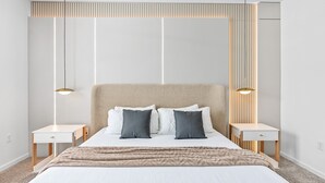 A modern bedroom with a large bed, two bedside tables, and a headboard with vertical lines. - Adventure Escape w Epic Themed Bedrooms Private Pool (Kissimmee)