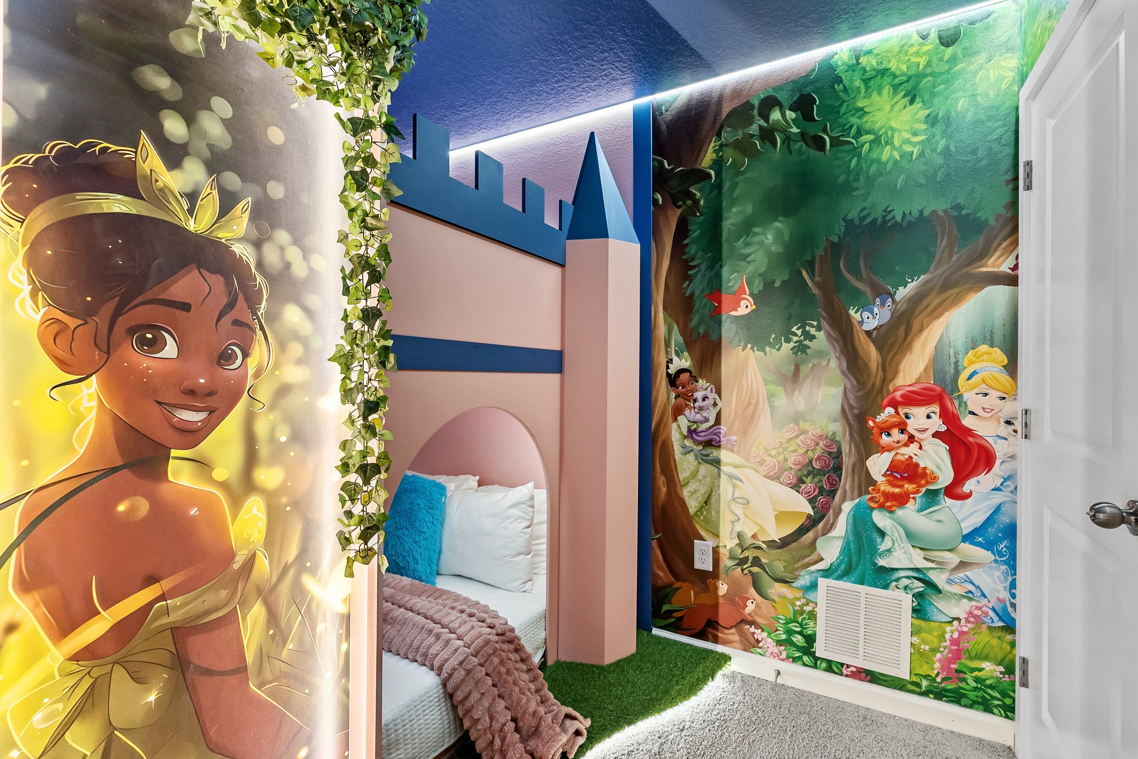 A child's bedroom with a castle mural, a bed with a pink headboard, and a window with a view of trees.