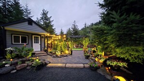 Il s’agit d’une propriété résidentielle dotée d’une allée pavée, d’une pergola en bois agrémentée de guirlandes lumineuses, ainsi que de divers pots de fleurs et arbustes.