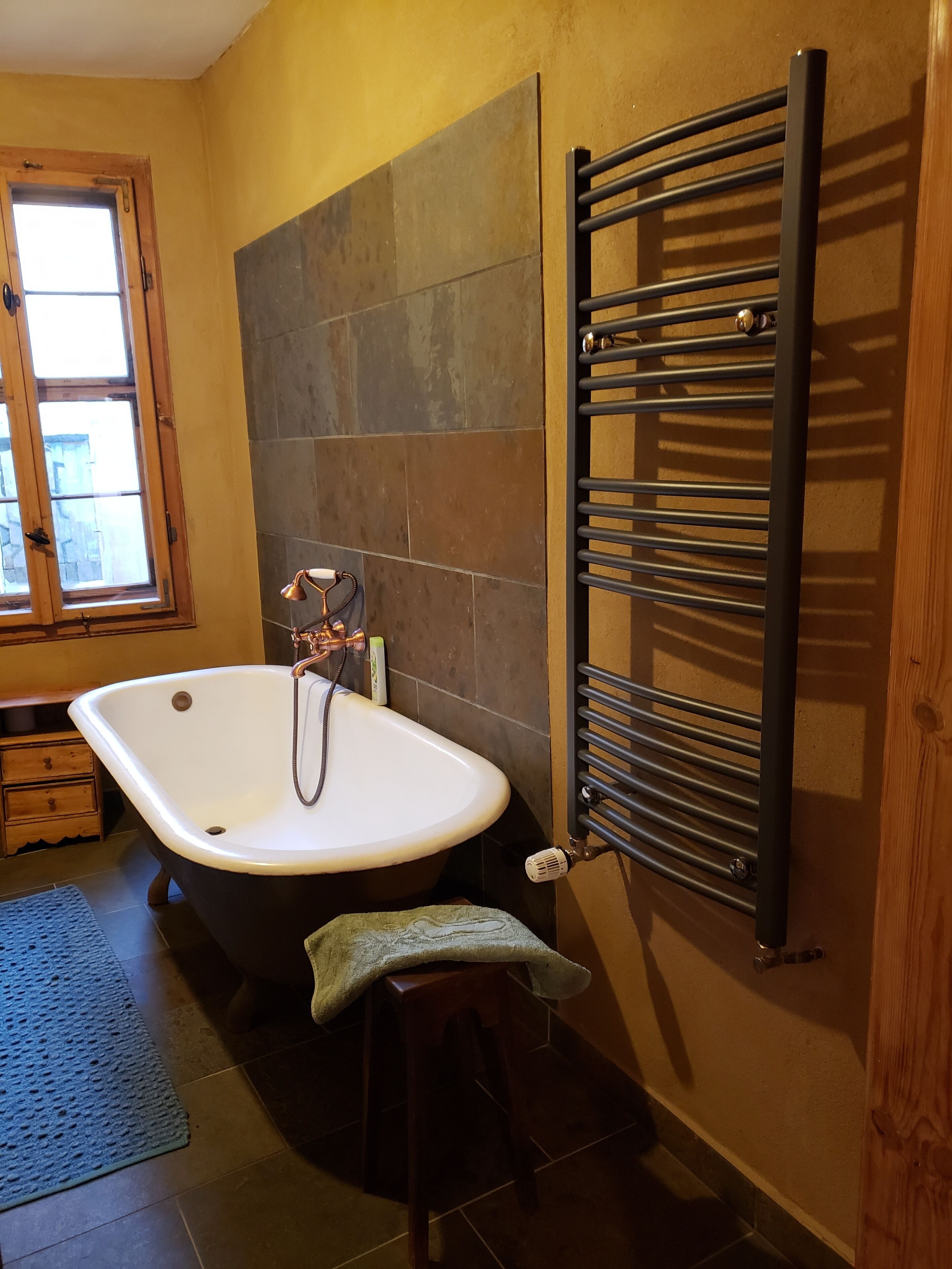 Ein Badezimmer mit freistehender Badewanne, einem Handtuchhalter und einem Fenster.