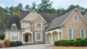 A two-story house with a stone facade, multiple windows, and a driveway. - Spacious 5-bedroom house in McDonough with a pool 35 minutes from Atlanta. (McDonough)