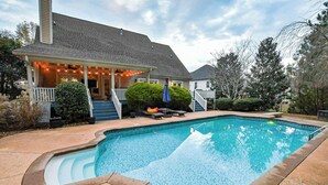A residential swimming pool with a covered patio, a staircase leading to the house, and a well-maintained lawn. - Spacious 5-bedroom house in McDonough with a pool 35 minutes from Atlanta. (McDonough)