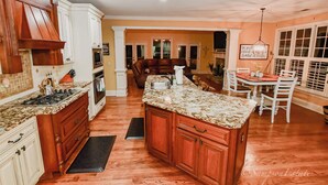 A spacious kitchen with wooden cabinets, a granite countertop, and a dining area with a table and chairs. - Spacious 5-bedroom house in McDonough with a pool 35 minutes from Atlanta. (McDonough)