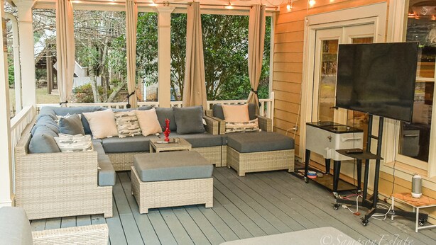 A covered outdoor seating area with wicker furniture, a ceiling fan, and a TV on a stand. - Spacious 5-bedroom house in McDonough with a pool 35 minutes from Atlanta. (McDonough)