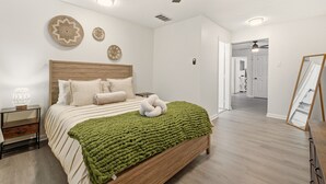 A bedroom with a wooden bed, a green blanket, and decorative wall art. - Stylish 3BR, 2BA 8m Away Expo Hub, 12m from Down Town Louisville, 12M from Derby (Louisville)