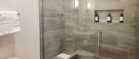 Un baño moderno con ducha de vidrio, inodoro y tocador con perchero.