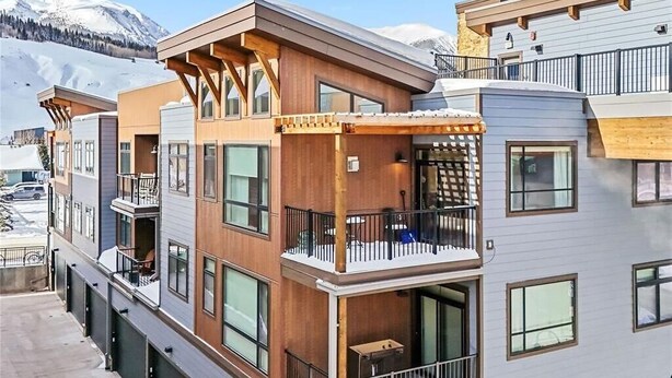 A multi-story residential building with balconies, large windows, and a snowy mountain backdrop. - Silverthorne Ski Loft - Garage Parking, Hot Tub, Downtown & Minutes to Slopes (Silverthorne)