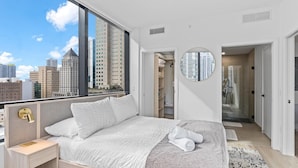 A modern bedroom with a large window, a round mirror, and a walk-in closet. - Downtown Building - Scenic waterfront walking (Miami)