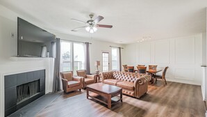 Uma sala de estar ampla com lareira, sofá de couro e área de jantar.