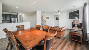 Uma sala de estar espaçosa com uma mesa de jantar de madeira, sofá de couro e uma pequena mesa lateral.