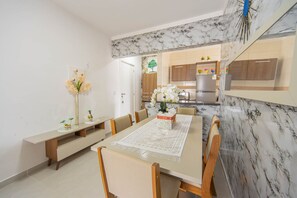 Un espace repas moderne avec un mur recouvert de marbre, des meubles en bois et une vue sur la cuisine.