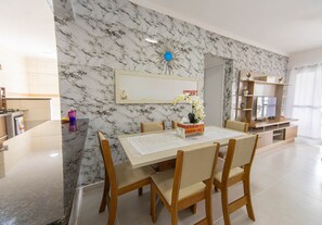 Un espace repas agrémenté d’un mur en marbre, d’un grand miroir et d’une table à manger en bois, ainsi que de chaises.
