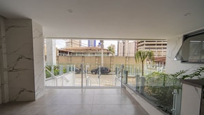 A spacious interior with a view of a parking area and buildings outside. - Apto com Garagem e Varanda a 450m da Praia (Praia Grande)