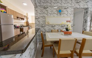 Une cuisine moderne dotée de plans de travail en marbre, de meubles en bois et d’un coin repas avec une table dressée pour quatre personnes.