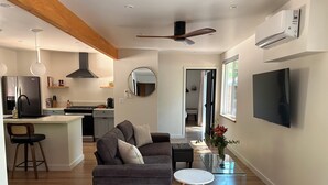Ein moderner Wohnraum mit einer Couch, einem Couchtisch und einem an der Wand montierten Fernseher.