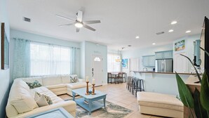 A modern living room with a sofa, coffee table, and a dining area with chairs and a table. - Coastal Villa, Walk to the Beach (Cape Canaveral)