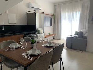 Ett modernt vardagsrum med en matplats, en platt-TV, en soffa och ett soffbord.