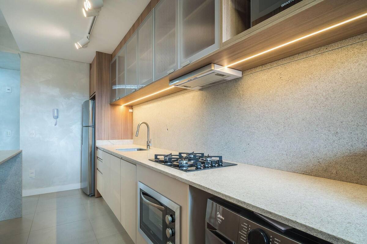 A modern kitchen with a gas stove, stainless steel appliances, and a light-colored countertop.