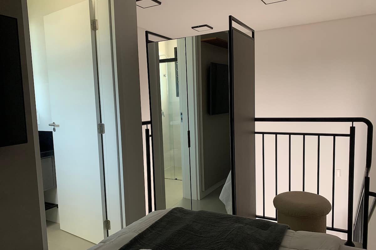 A bedroom with a bed, a bedside table, a mirror, and a wardrobe.