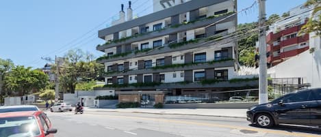 Un edificio de varios pisos con balcones, una entrada visible y coches aparcados.