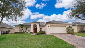 A residential house with a red door, a garage, and a well-maintained lawn. - Perfect pool & spa villa near Disney World (Davenport)