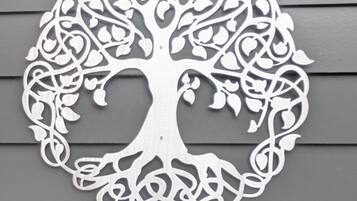 A white, intricate tree-shaped wall decor against a grey wall.