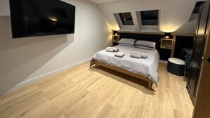 Un dormitorio moderno con una cama grande, un televisor de pantalla plana en la pared y tragaluces.