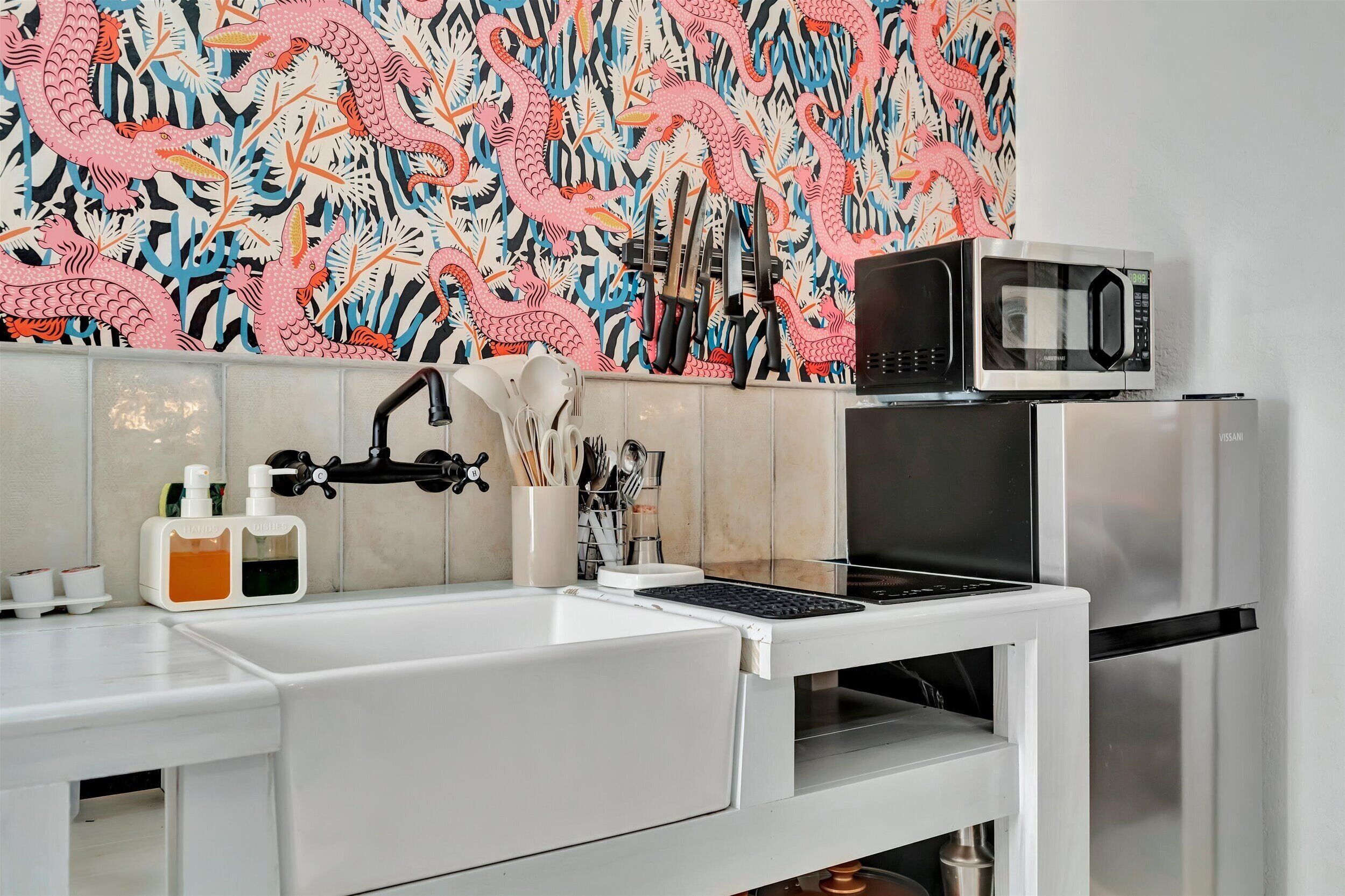 Una cocina moderna con encimera blanca, un fregadero, microondas y refrigerador.
