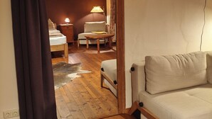 En hyggelig stue med trægulv, en beige sofa, et træbord og et fjernsyn ophængt på væggen.